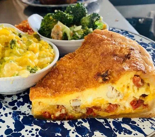 A plate with a slice of quiche, a bowl of broccoli, and a bowl of macaroni and cheese.
